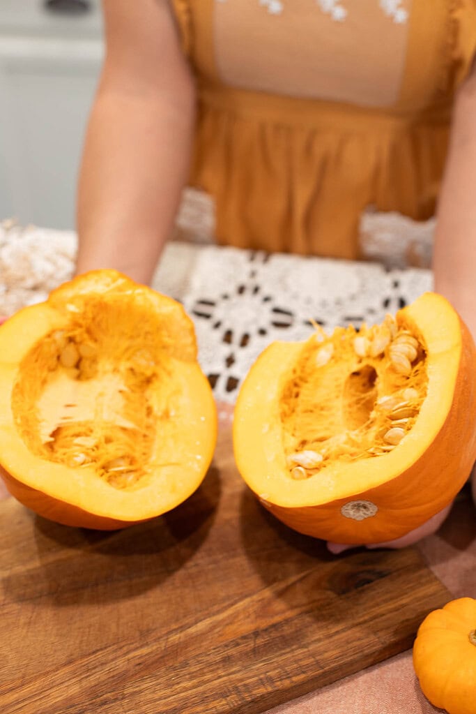 Fresh pumpkin cut in half showing seeds and stringy center before roasting