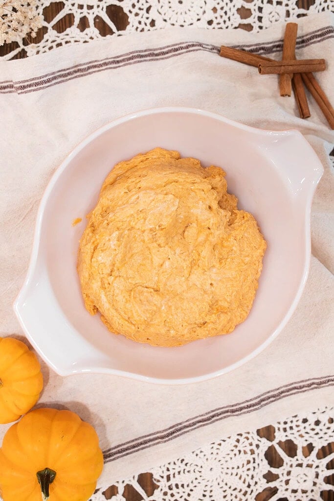 Sourdough pumpkin muffin batter in white mixing bowl ready for baking with cinnamon sticks nearby