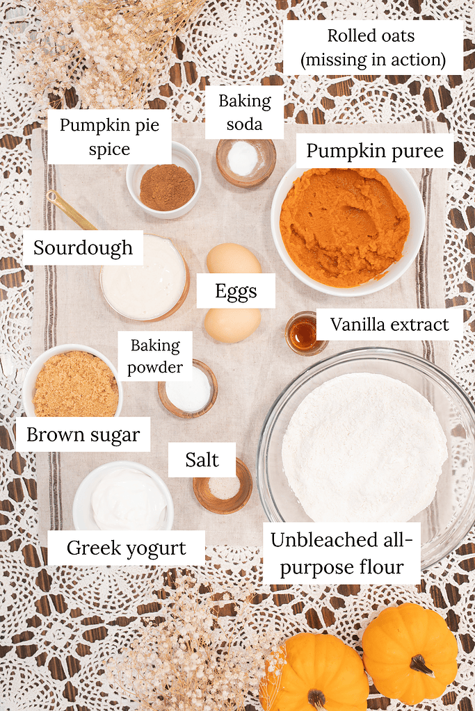 Sourdough pumpkin muffin ingredients including pumpkin puree, eggs, flour, brown sugar, and spices on table
