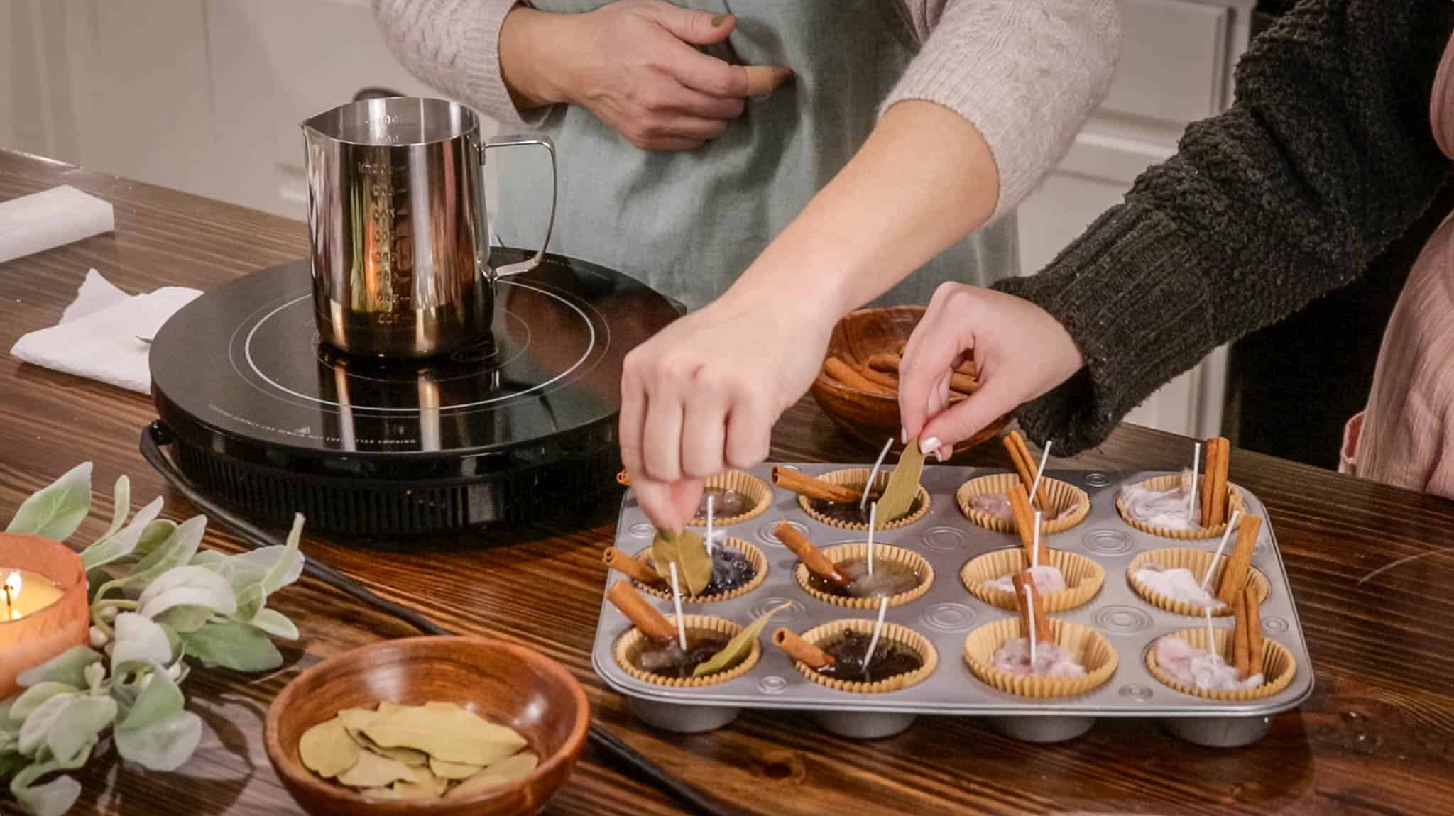 a women placing bay leaves into melted fire starters in a muffin tin in a cottage kitchen
