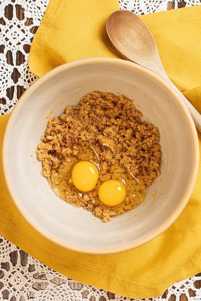 Eggs added to creamed butter and brown sugar mixture in a bowl for sourdough banana muffins.
