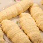 A plate full of cookie sourdough lady fingers on floral pink antique china plate in a kitchen on a wooden counter top.