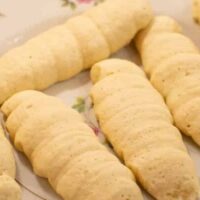 A plate full of cookie sourdough lady fingers on floral pink antique china plate in a kitchen on a wooden counter top.