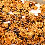 A pan of coked granola homemade in a cottage kitchen on a silver baking pan.