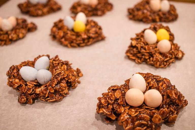 A photo of several chocolate oatmeal cookies on parchment paper in a kitchen.