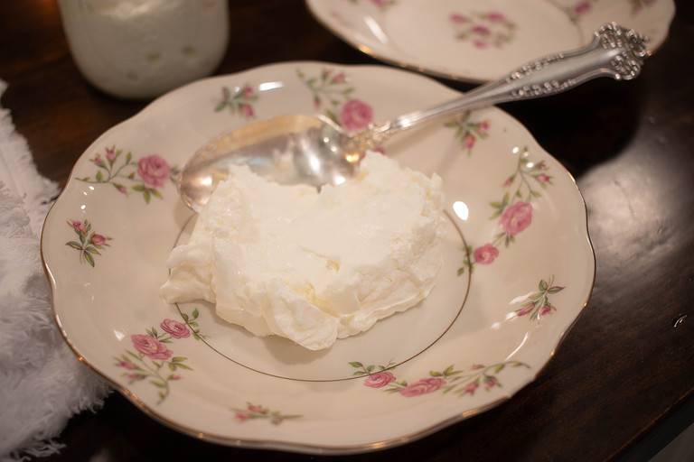 A small pink china bowl with a spoon and yogurt in the bowl.