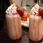 two strawberry frappucinos topped with whipped cream drizzled with strawberry simple syrup