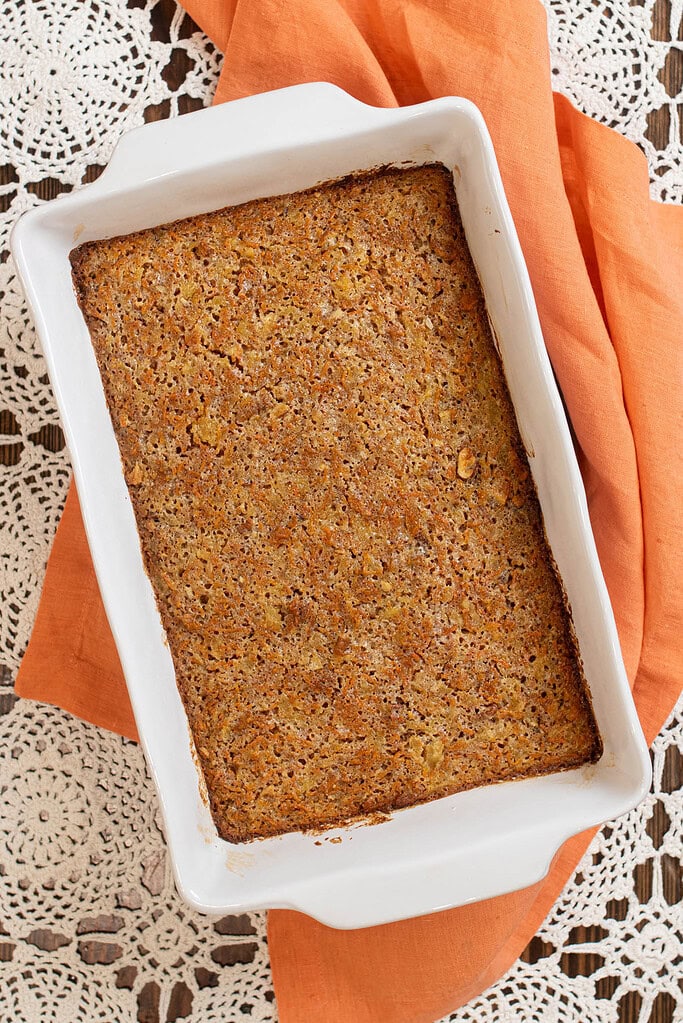 Freshly baked carrot cake in a white baking dish with a golden brown top.