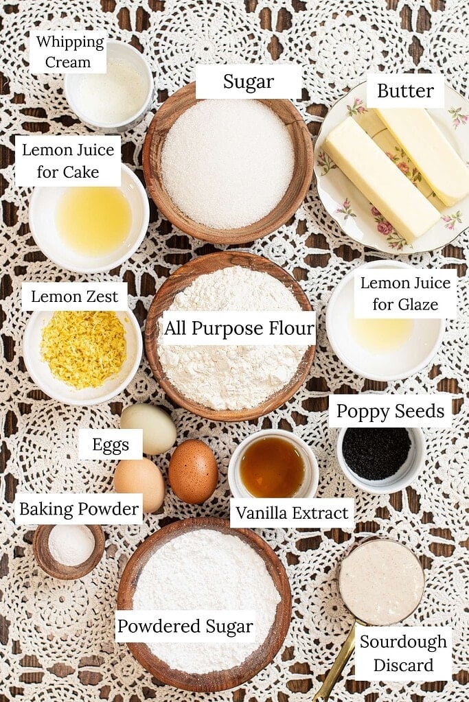 Ingredients for sourdough lemon poppy seed pound cake including flour, sugar, butter, eggs, lemon zest, lemon juice, poppy seeds, sourdough discard, and powdered sugar.