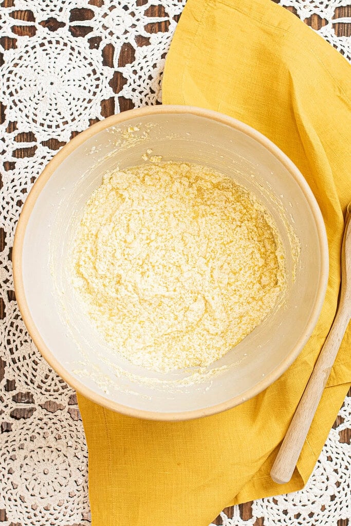 Dry ingredients mixed in a bowl for sourdough lemon poppy seed pound cake batter on a yellow linen cloth.