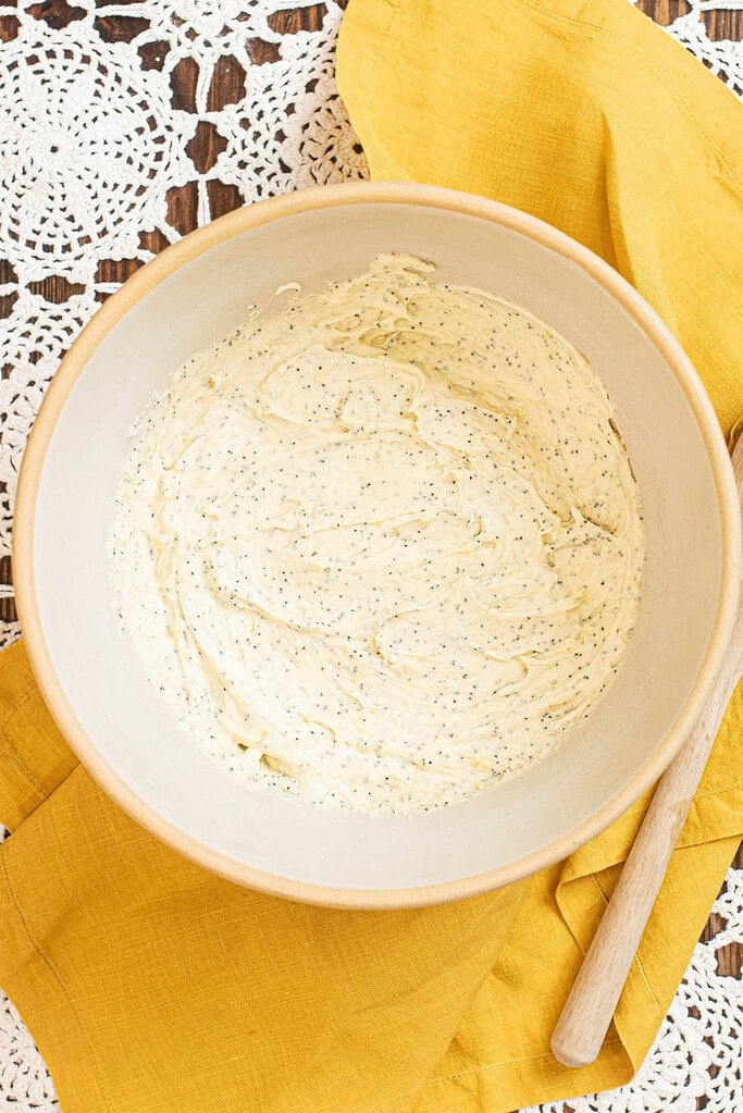 Sourdough lemon poppy seed pound cake batter fully mixed with visible poppy seeds in a large bowl.