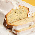 Close-up of sliced sourdough lemon poppy seed pound cake showing moist crumb and lemon glaze dripping over the edges.
