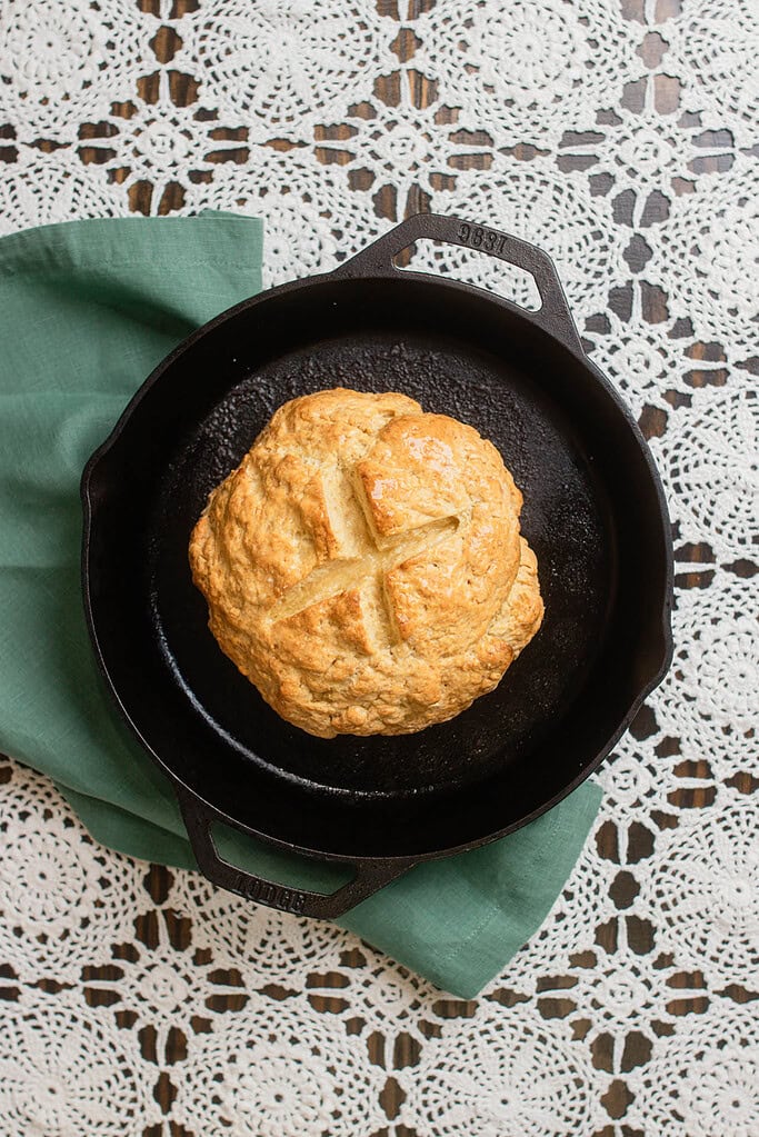 Freshly baked Irish soda bread in a cast iron skillet with a golden crust and the traditional cross cut on the top.
