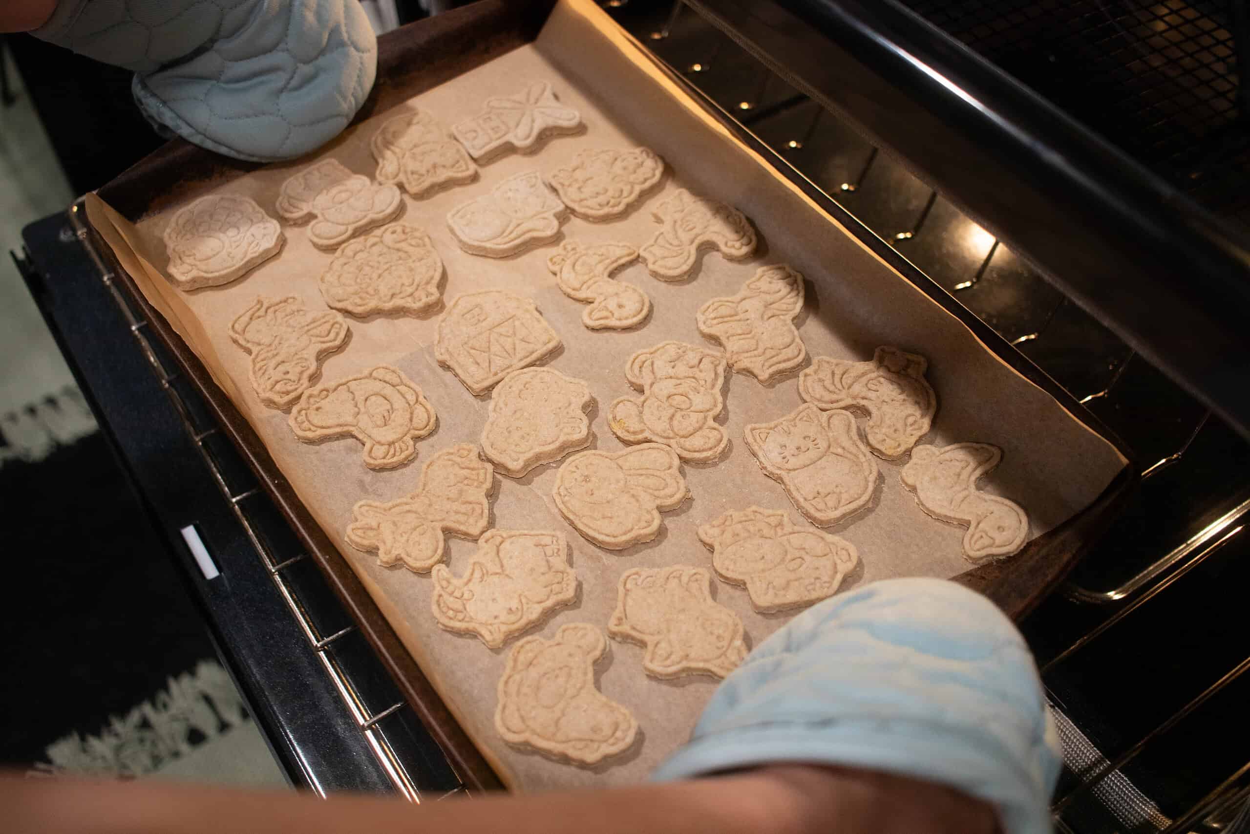 a woman pulling animal crackers out of the oven