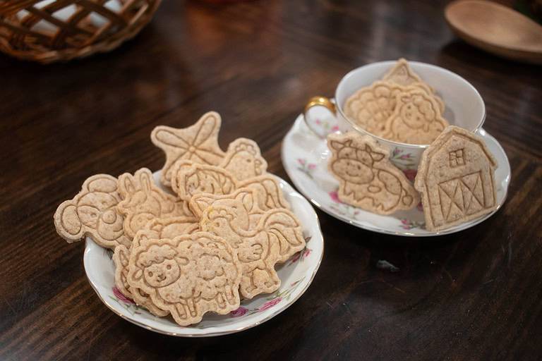 a small pink floral china plate of animal crackers on a wooden countertop