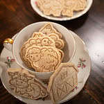 a vertical image of animal crackers in a pink floral china cup on a wooden countertop in a cottage kitchen