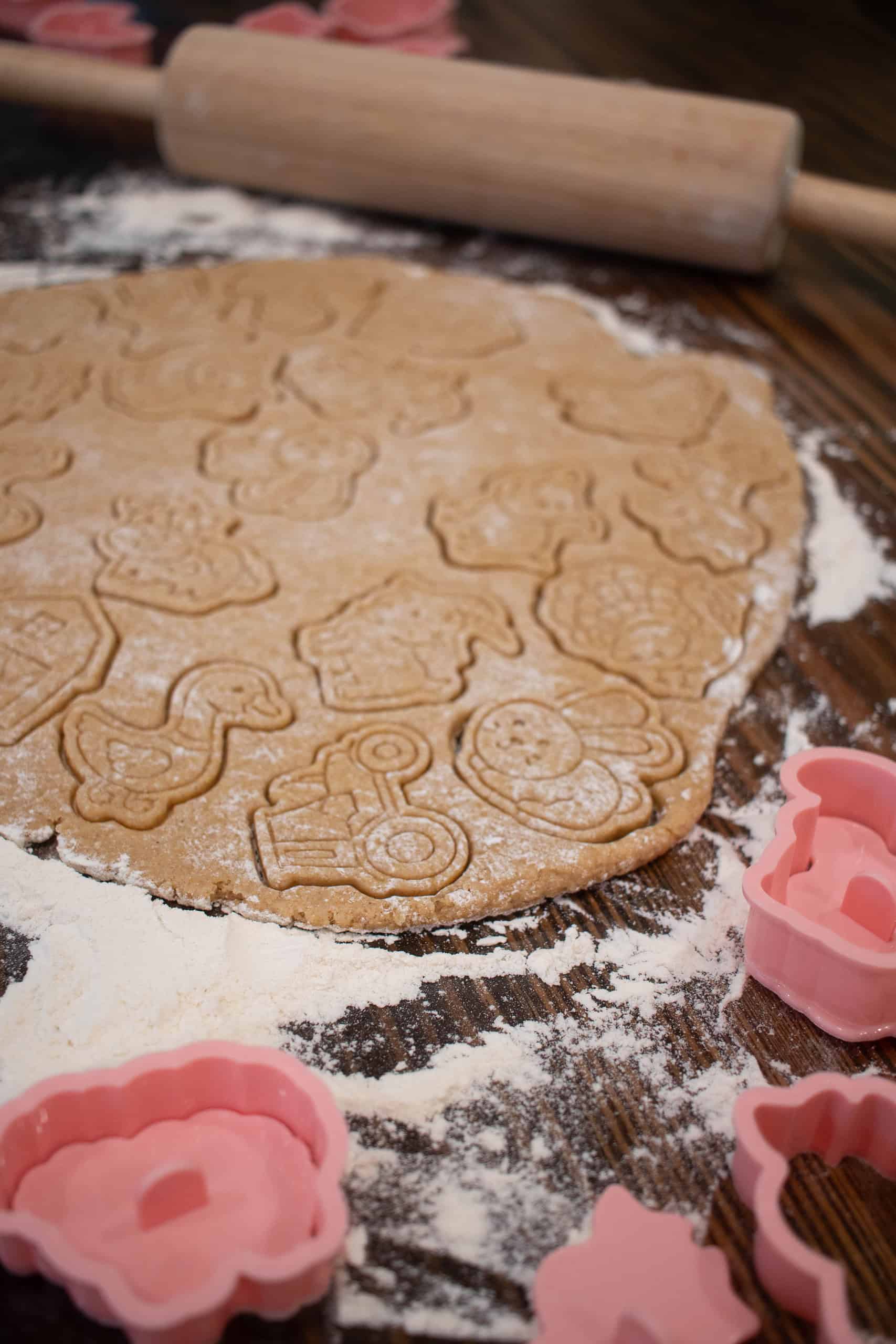 dough for sourdough animal crackers cut out into animal chapes on wooden counter top
