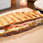 a sourdough panini grilled cheese sandwich on a piece of parchment paper in a cottage kitchen