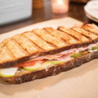 a sourdough panini grilled cheese sandwich on a piece of parchment paper in a cottage kitchen