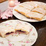 a a jam filled sourdough pop tart cut into two on a pink rose china plate with a platter of pop tarts in the background