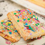 Glazed sourdough discard pop-tarts with colorful sprinkles stacked on a vintage floral plate.