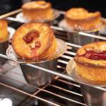 a close up of sourdough raspberry popovers in a silver popover pan on a wire rack