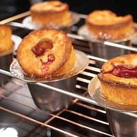 a close up of sourdough raspberry popovers in a silver popover pan on a wire rack