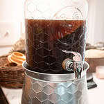 a two gallon drink dispenser on a marble countertop filled with kombucha in a cottage kitchen