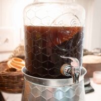 a two gallon drink dispenser on a marble countertop filled with kombucha in a cottage kitchen