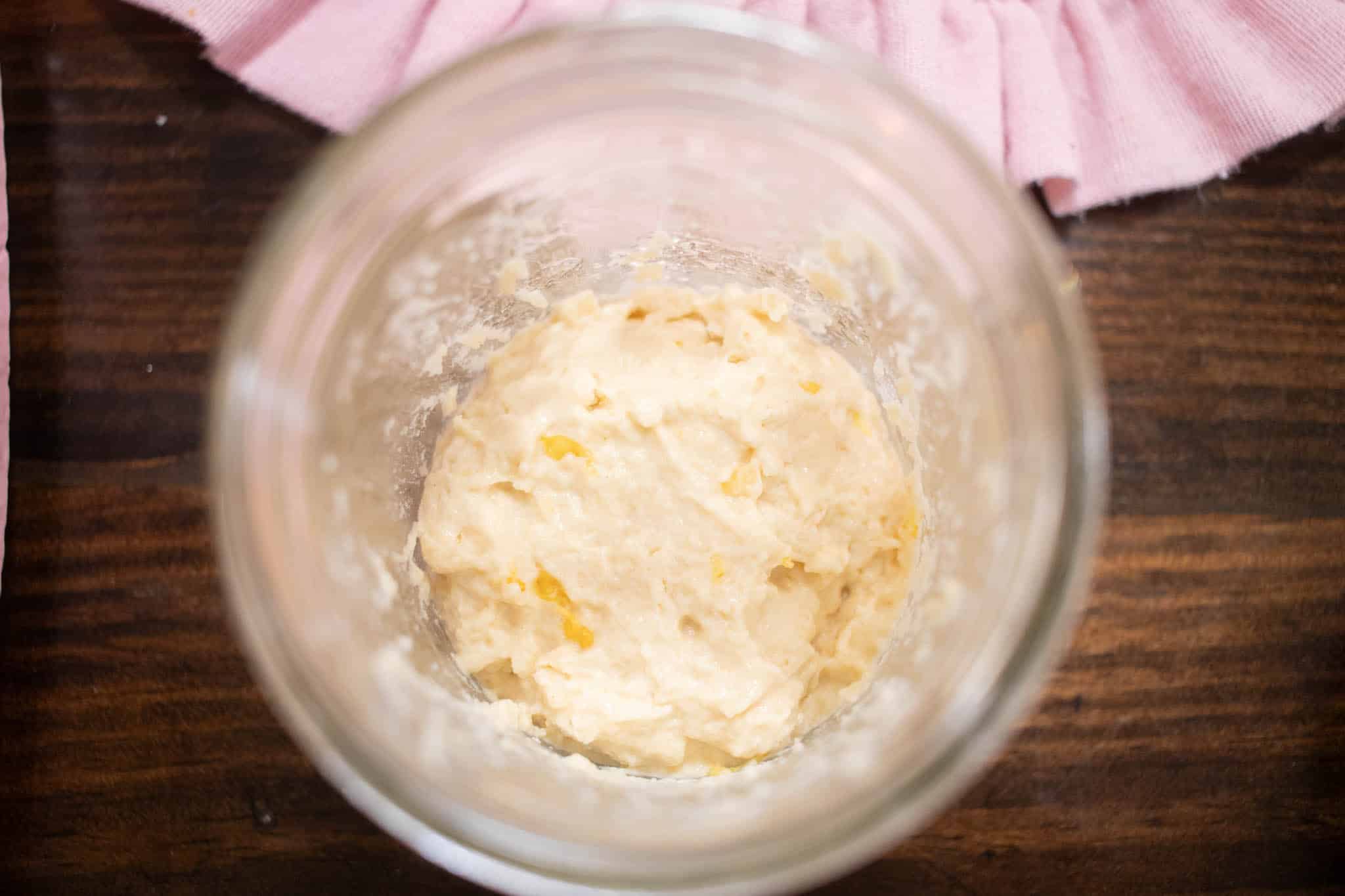 a overhead shot of the inside of a jar of sourdough starter on a wooden counter top in a cottage kitchen