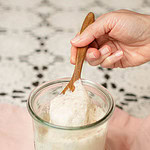 Wooden spoon lifting stretchy sourdough starter from a glass jar, showing elastic texture and active fermentation.