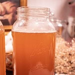 a half gallon sized mason jar filled with water kefir and white babys breath in the background in a cosy cottage kitchen