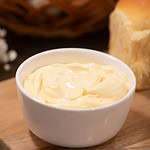 a white small bowl of mayonnaise on a wooden cutting board in a cottage kitchen