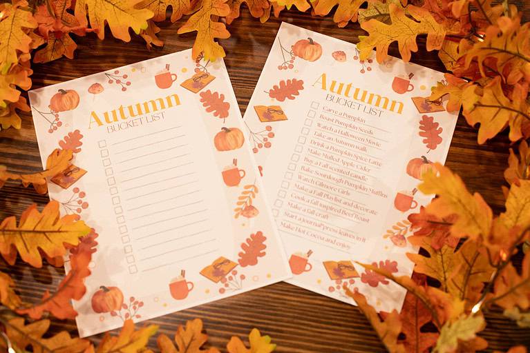 a picture of 2 the modern day cottages free printable autumn bucket list one blank and one filled out on a wooden counter top in a cozy cottage