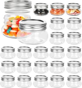 Collection of twenty-four small 4 oz clear mason jars with silver metal lids, some filled with candy and spices.