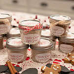 A closer angle of sugar scrub jars stacked and decorated for Christmas gifting, surrounded by cozy holiday accents.