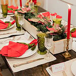 cozy cottage christmas tablescape with red candles greenery centerpiece and festive place settings