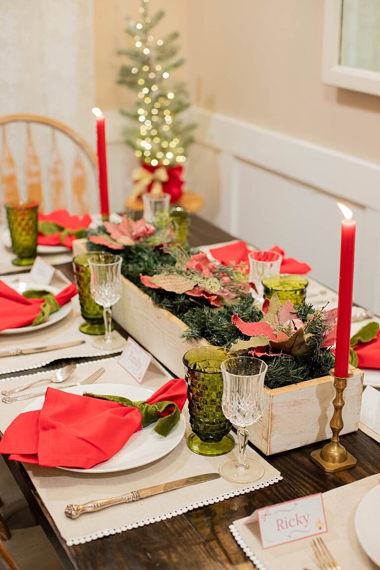 cozy cottage christmas tablescape with red candles greenery centerpiece and festive place settings