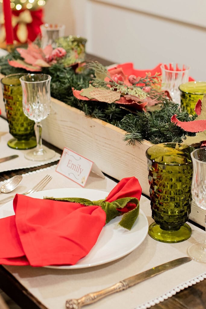 christmas place setting with red napkin green ribbon and holiday table centerpiece