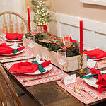 An angled view of the holiday table with detailed elements, including gold accents, gingham patterns, and personalized place cards.