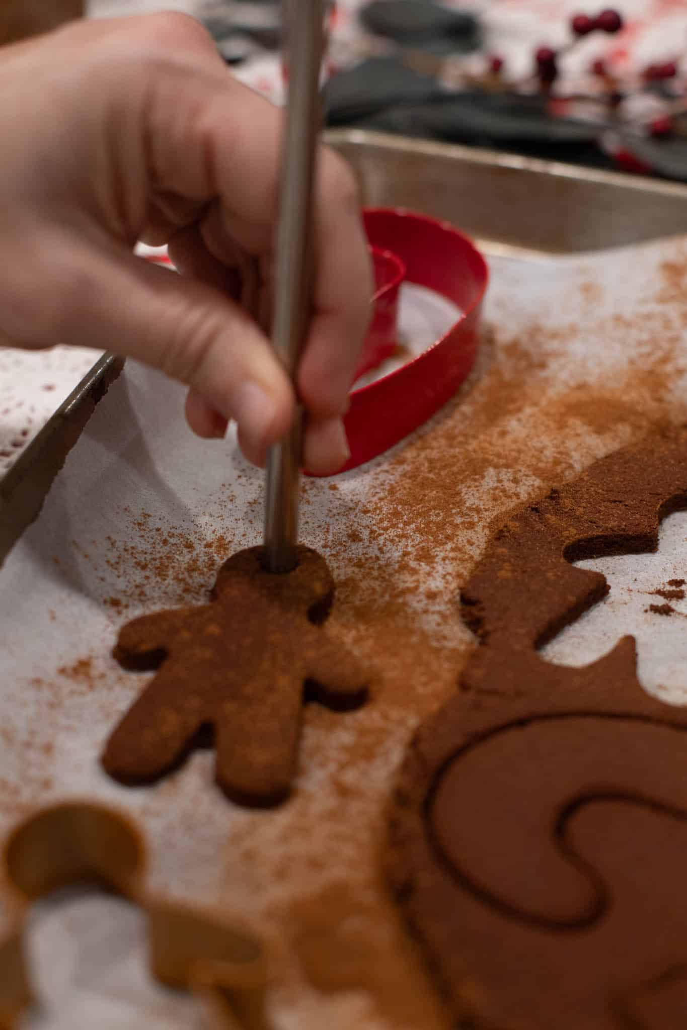 A hand holding a gingerbread-shaped cinnamon applesauce ornament, showing the process of creating them.
