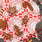 Cinnamon applesauce ornaments in festive shapes like gingerbread people and stars, displayed on a red and white holiday tablecloth.