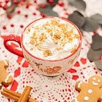 homemade gingerbread latte with whipped cream and crushed cookies in holiday mug on cozy winter setting