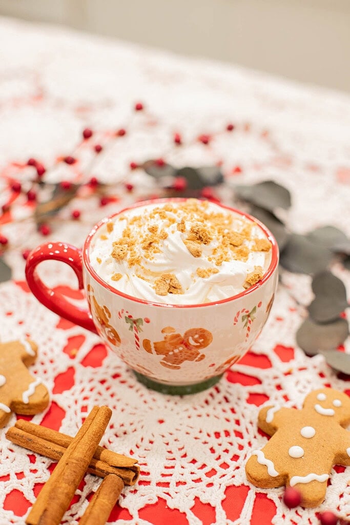 finished gingerbread latte with whipped cream and cookie topping in cozy holiday setting