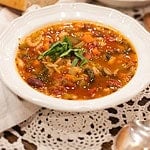Two bowls of hearty minestrone soup served with a crusty baguette on the side, garnished with fresh basil and Parmesan cheese for a cozy presentation.