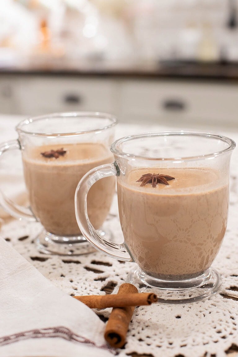 Creamy homemade chai latte in clear glass mugs with star anise garnish and cinnamon sticks