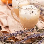 Close-up of two honey lavender London Fog lattes garnished with dried lavender, styled on a copper tray with a copper kettle in the background.