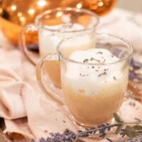 Close-up of two honey lavender London Fog lattes garnished with dried lavender, styled on a copper tray with a copper kettle in the background.