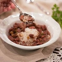 A hand lifting a spoonful of red beans and rice, capturing the tender beans, slices of sausage, and fluffy rice in a comforting bite.