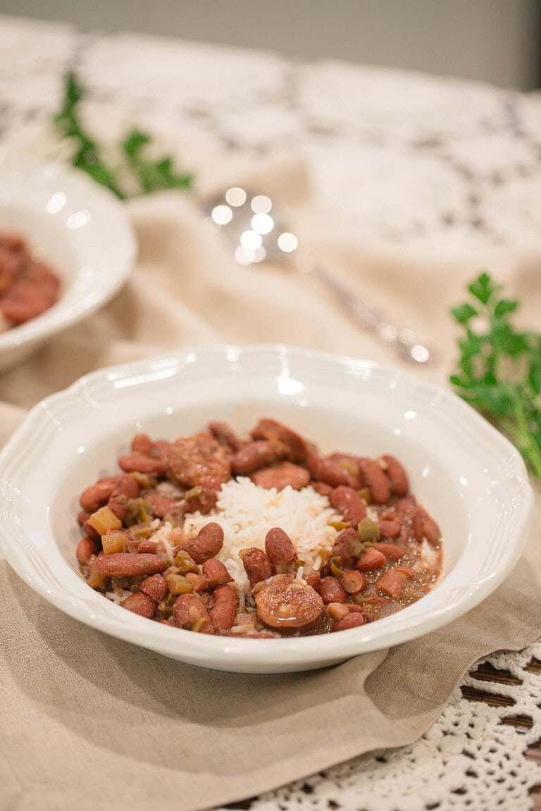Bowl of New Orleans–style red beans and rice with sliced sausage served on a linen napkin
